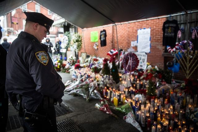 A police officer pays his respect at the memorial site on Tuesday